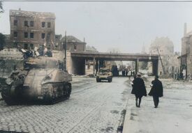 Des chars américains passant sous le pont Albert 1er,  se dirigeant vers l'avenue de Valenciennes, 2 personnes de la défense passive sur le trottoir opposé au cimetière Porte Notre Dame