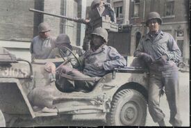 Jeep garé avec à son bord 3 soldats américains dont un lisant un plan, un autre qui s'appuie sur la mitrailleuse munie de jumelle, un autre s'accoudant sue la jeep et un autre regardant le plan à distance