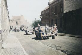 Défilé de jeep et de camions remplis de soldats armés roulant dans une rue 